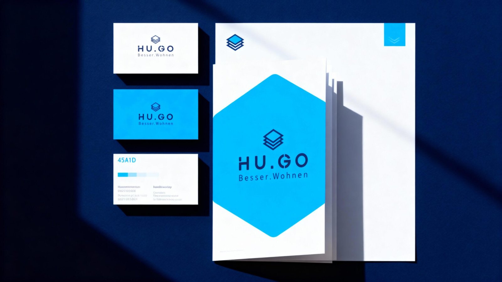 http://Design%20der%20Markenidentität%20von%20HU.GO%20mit%20Logo,%20Visitenkarten%20und%20Briefpapier%20in%20Blau%20und%20Weiß,%20das%20den%20Slogan%20Besser.Wohnen%20präsentiert.