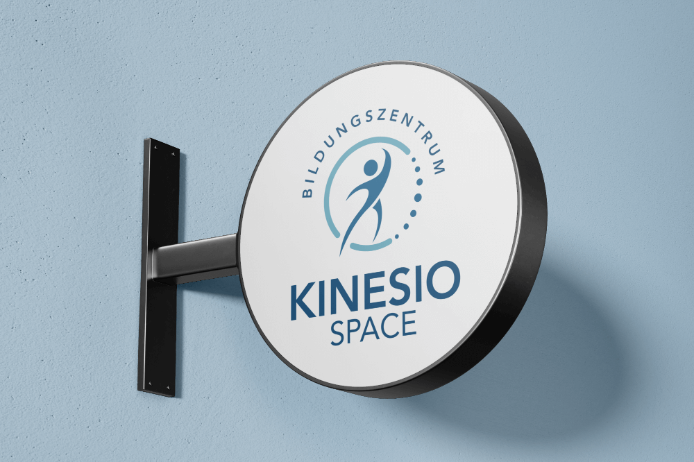http://Rundes%20Schild%20des%20Bildungszentrums%20Kinesio%20Space%20an%20einer%20blauen%20Wand,%20mit%20einem%20modernen%20Logo,%20das%20Bewegung%20und%20Gesundheit%20symbolisiert.