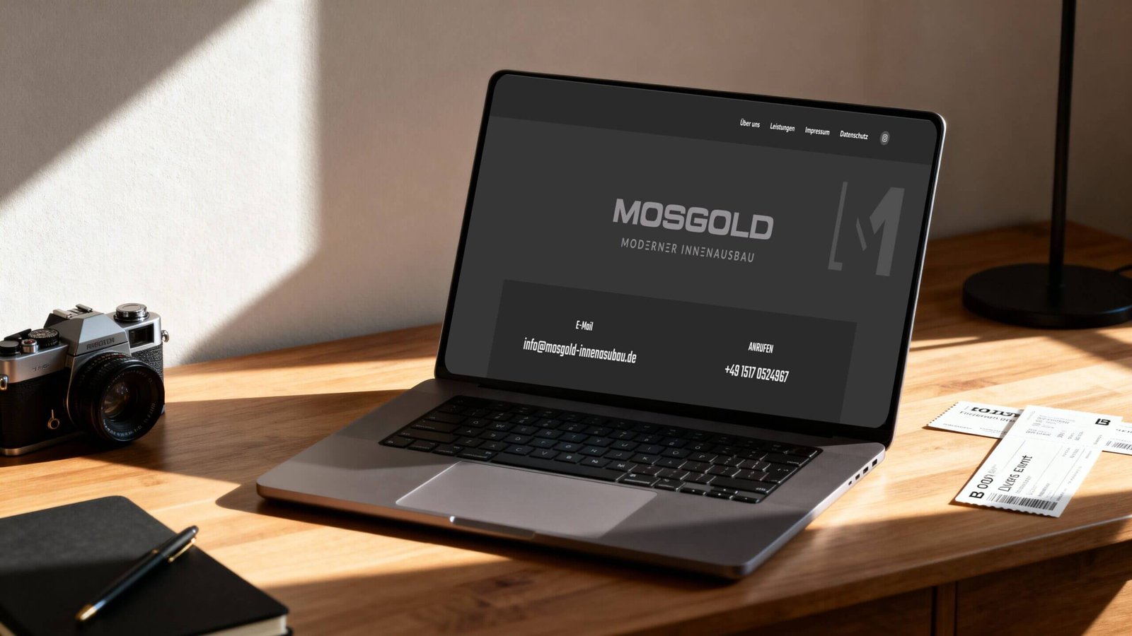 http://Laptop%20auf%20einem%20Holztisch%20mit%20einer%20Kamera%20und%20Notizbuch,%20zeigt%20die%20Website%20von%20Mosgold,%20einem%20Anbieter%20für%20modernen%20Innenausbau.