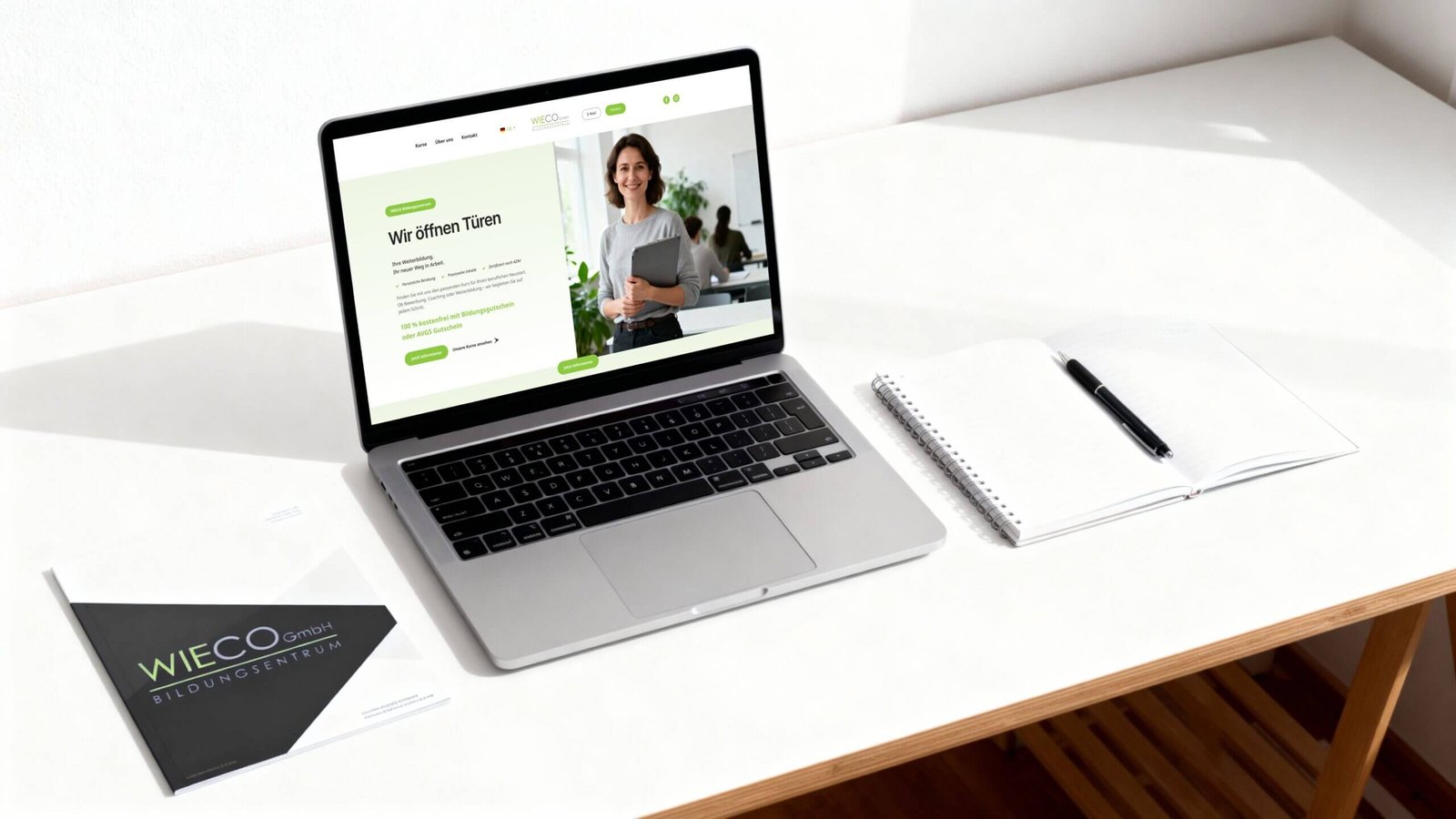 http://Laptop%20mit%20geöffneter%20Webseite%20des%20WIECO%20Bildungszentrums,%20auf%20dem%20eine%20lächelnde%20Frau%20mit%20einem%20Ordner%20zu%20sehen%20ist.%20Daneben%20liegen%20ein%20Notizbuch%20und%20ein%20Stift%20auf%20einem%20weißen%20Tisch.