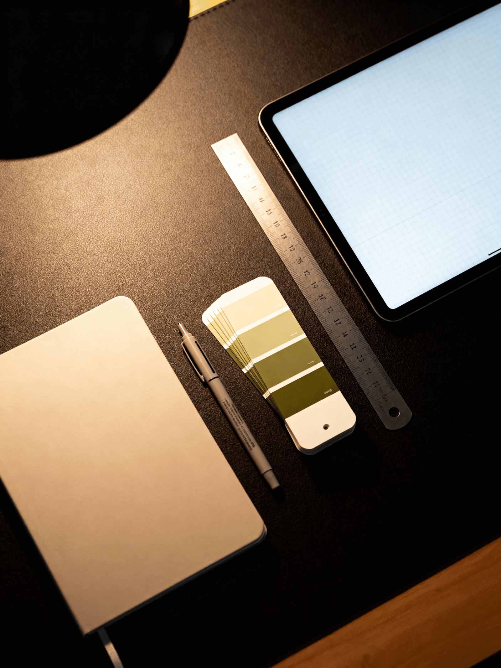 http://Schreibtisch-Arrangement%20mit%20Notizbuch,%20Stift,%20Farbmustern%20in%20Grüntönen,%20einem%20Lineal%20und%20einem%20Tablet%20auf%20einem%20dunklen%20Untergrund.%20Ideal%20für%20kreative%20Arbeiten%20und%20Designprojekte.